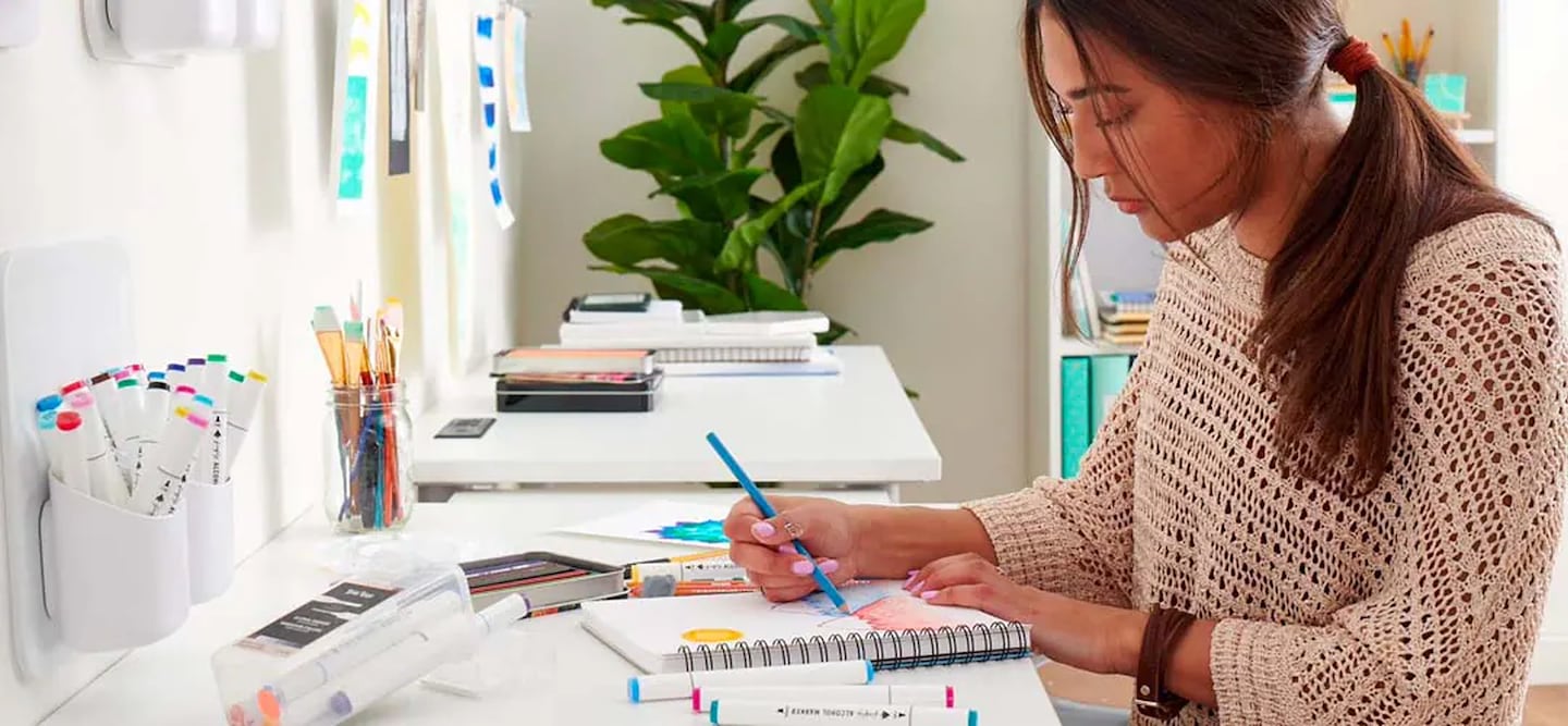 Woman drawing with art supplies in notebook