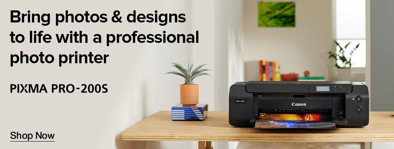 Canon PIXMA PRO-200S photo printer banner showing professional printer producing a high quality photo print on a desk with home office decor and shop now call to action