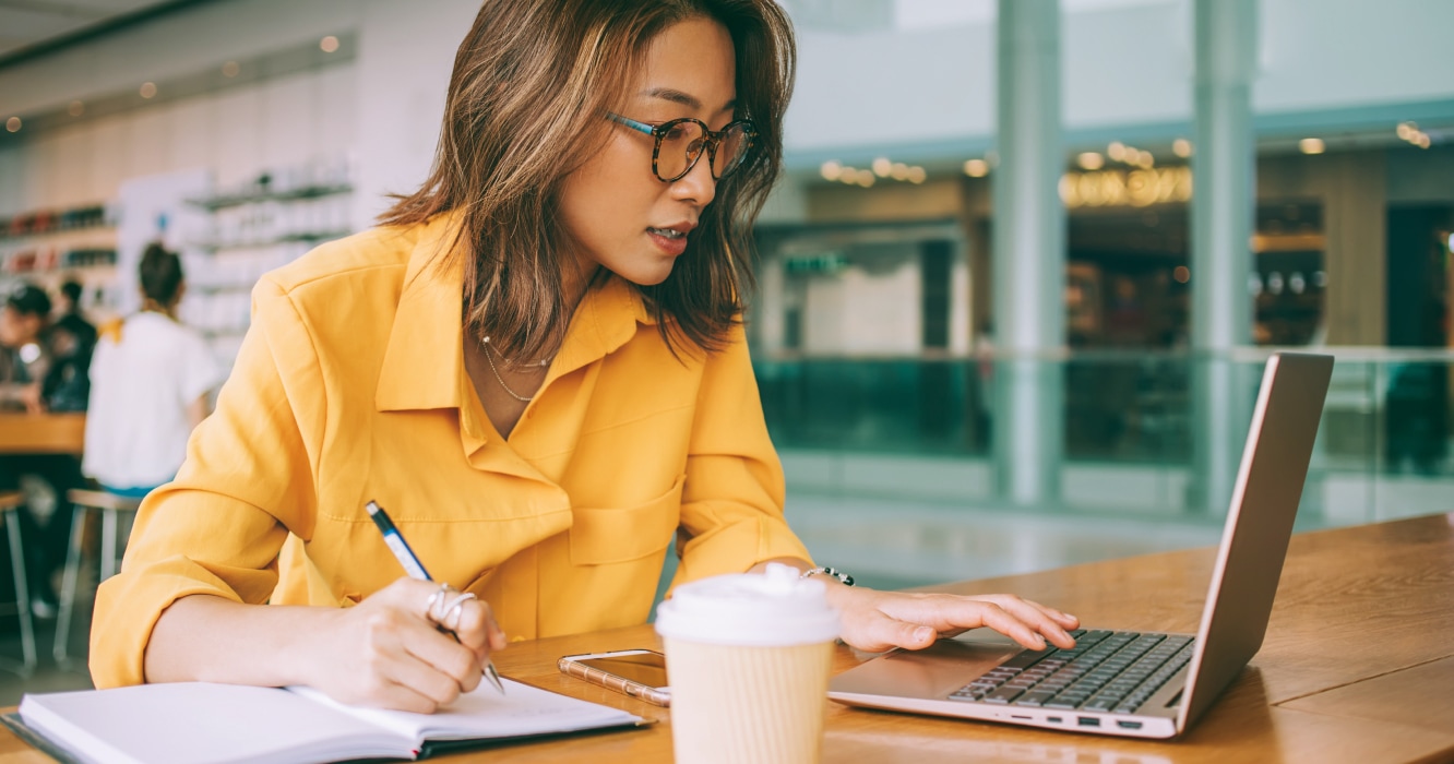 How to work remotely from anywhere. Whether you're new to remote work or a seasoned digital nomad, these tips will help you make the most of your bleisure trip. Women working on a laptop with notebook and pen. https://www.staples.com/stores/articles/working/how-to-work-remotely-anywhere-tips-for-traveling--working.html