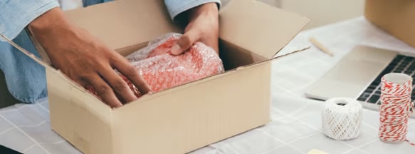 A package being packed into a cardboard shipping box
